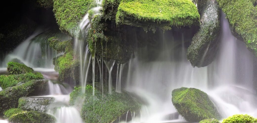 Wasserfall über Steinen mit Moos